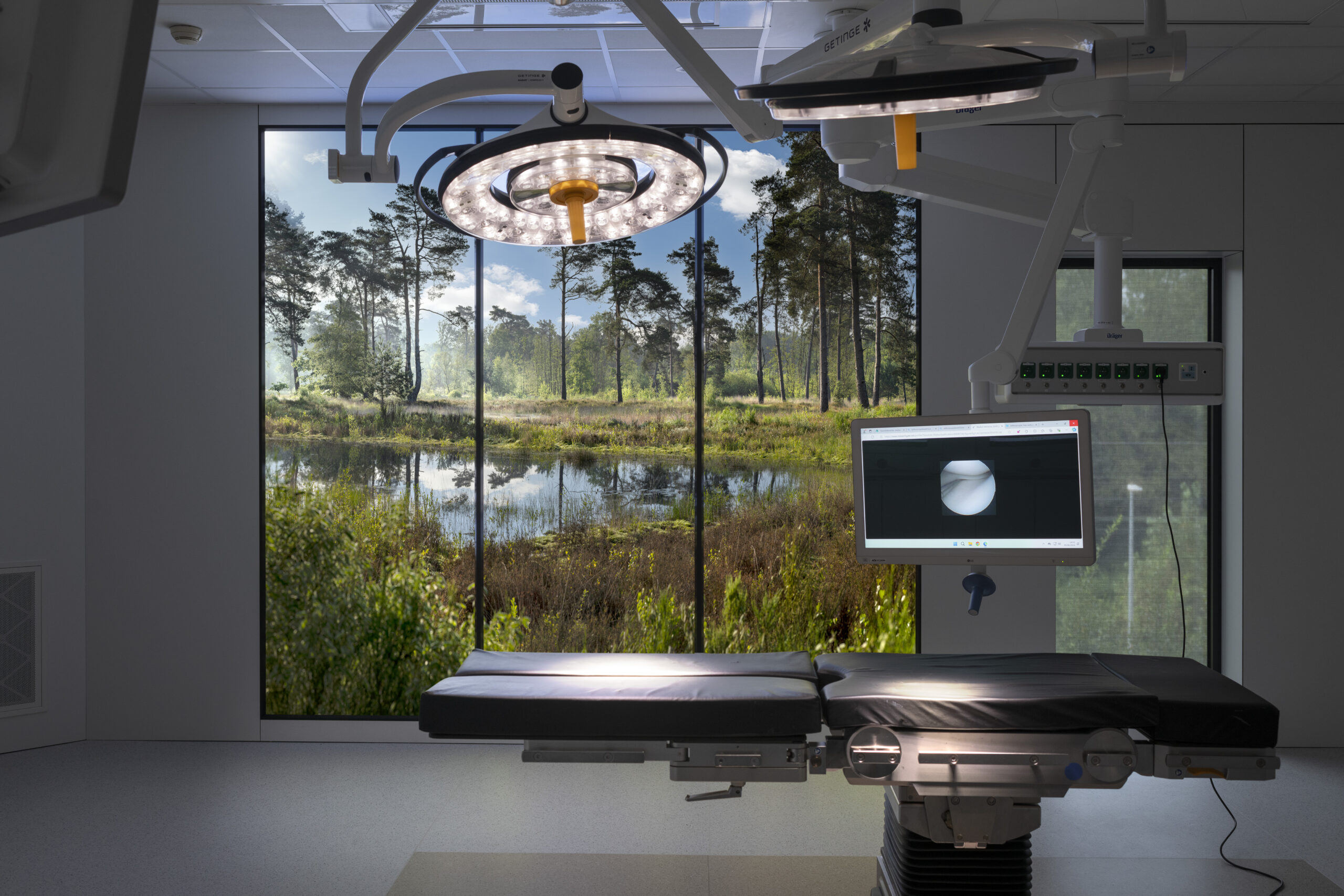 Operatiekamer met een LED-fotowand die een natuurlandschap met dennenbomen en water toont