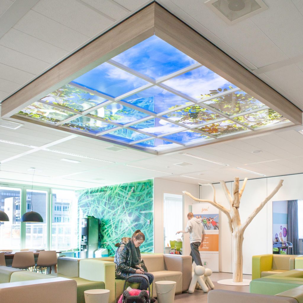 Wachtruimte van De Kinderkliniek met een groot LED-fotoplafond met lucht en boomtakken