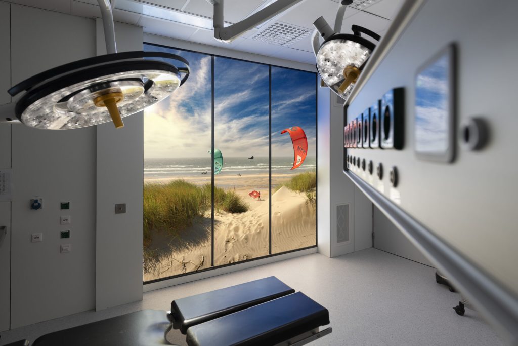 Operatiekamer met een LED-fotowand die een strand met duinen en zee toont